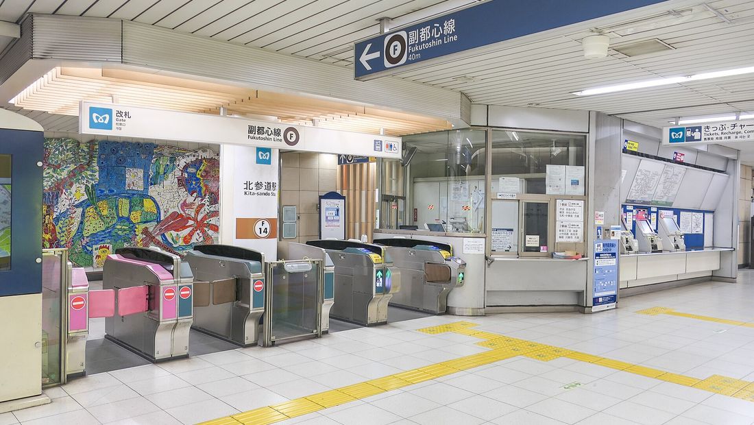 Subway ticket gates with an attended window beside them and a ticket machine area to the right.